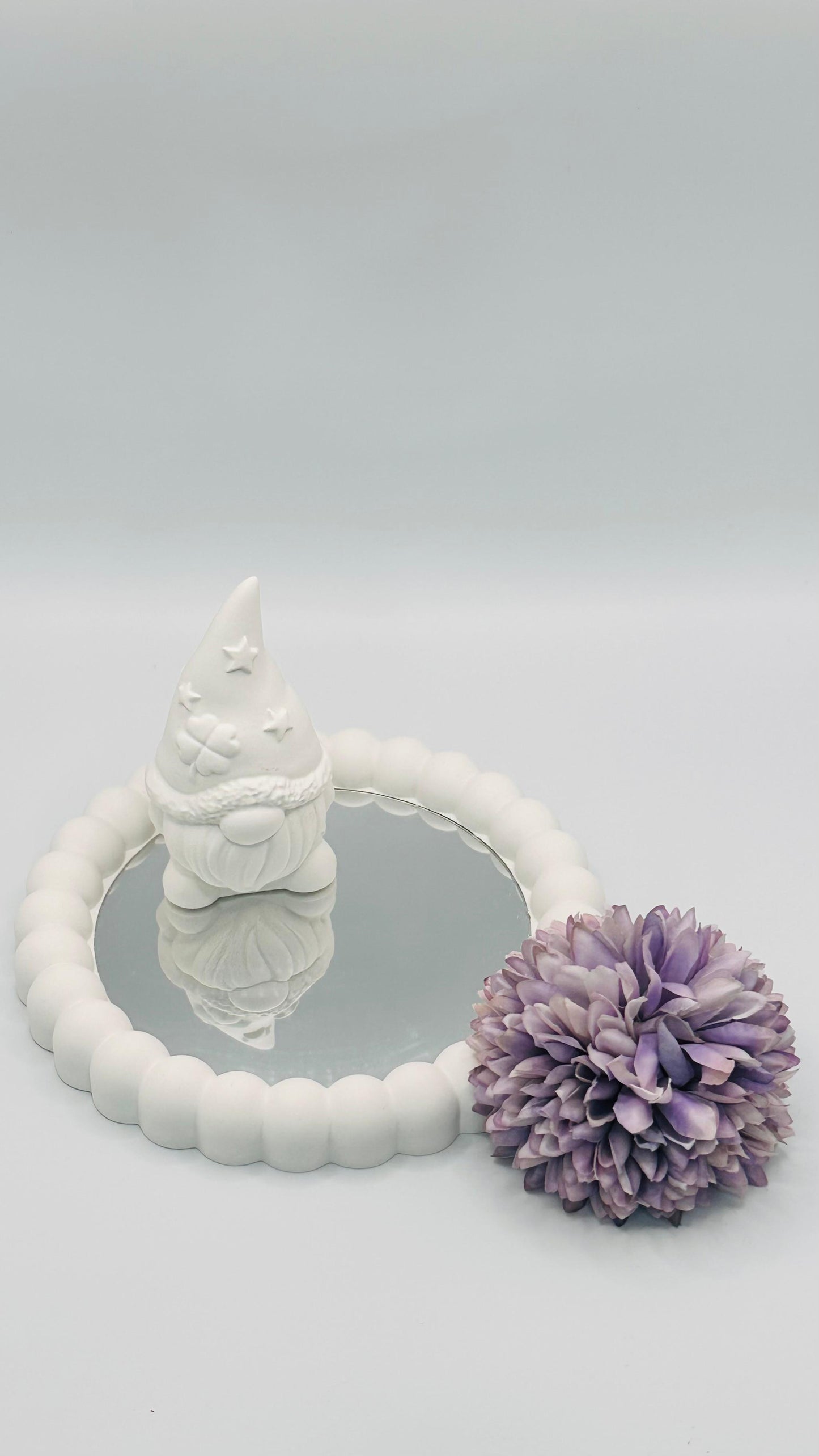 Runder Bubble-Spiegel aus Keracraft mit kleinem Keracraft-Wichtel darauf, dekoriert mit einer violetten Kunstblume.
Herzberg Crafts