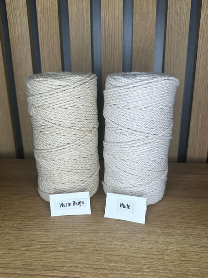 Zwei große Garnrollen aus gedrehtem Baumwollgarn in den Farben Warm Beige und Nude, auf einem Holztisch vor vertikaler Holzrückwand, jeweils mit Farbkärtchen beschriftet.
Herzberg Crafts