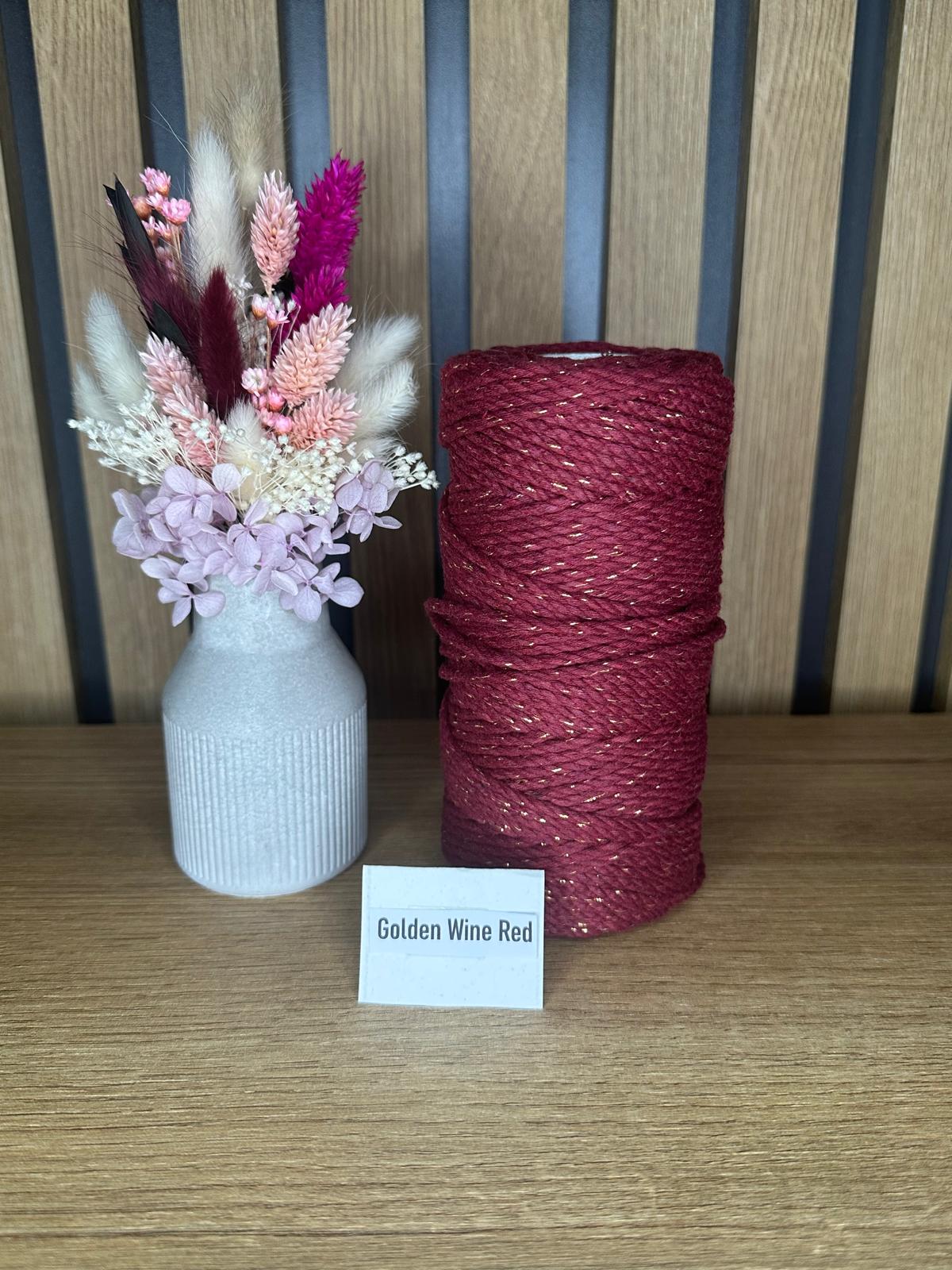 Garnrolle in der Farbe Golden Wine Red mit feinen goldfarbenen Glanzfasern, stehend neben einer Vase mit Trockenblumen auf einem Holztisch vor Holzrückwand.
Herzberg Crafts