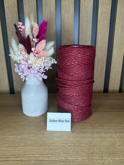 Garnrolle in der Farbe Golden Wine Red mit feinen goldfarbenen Glanzfasern, stehend neben einer Vase mit Trockenblumen auf einem Holztisch vor Holzrückwand.
Herzberg Crafts