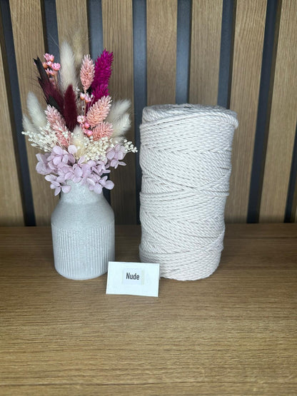 Helle Garnrolle aus gedrehter Baumwollkordel in der Farbe Nude, arrangiert neben einer Vase mit rosafarbenen Trockenblumen auf einem Holztisch.
Herzberg Crafts