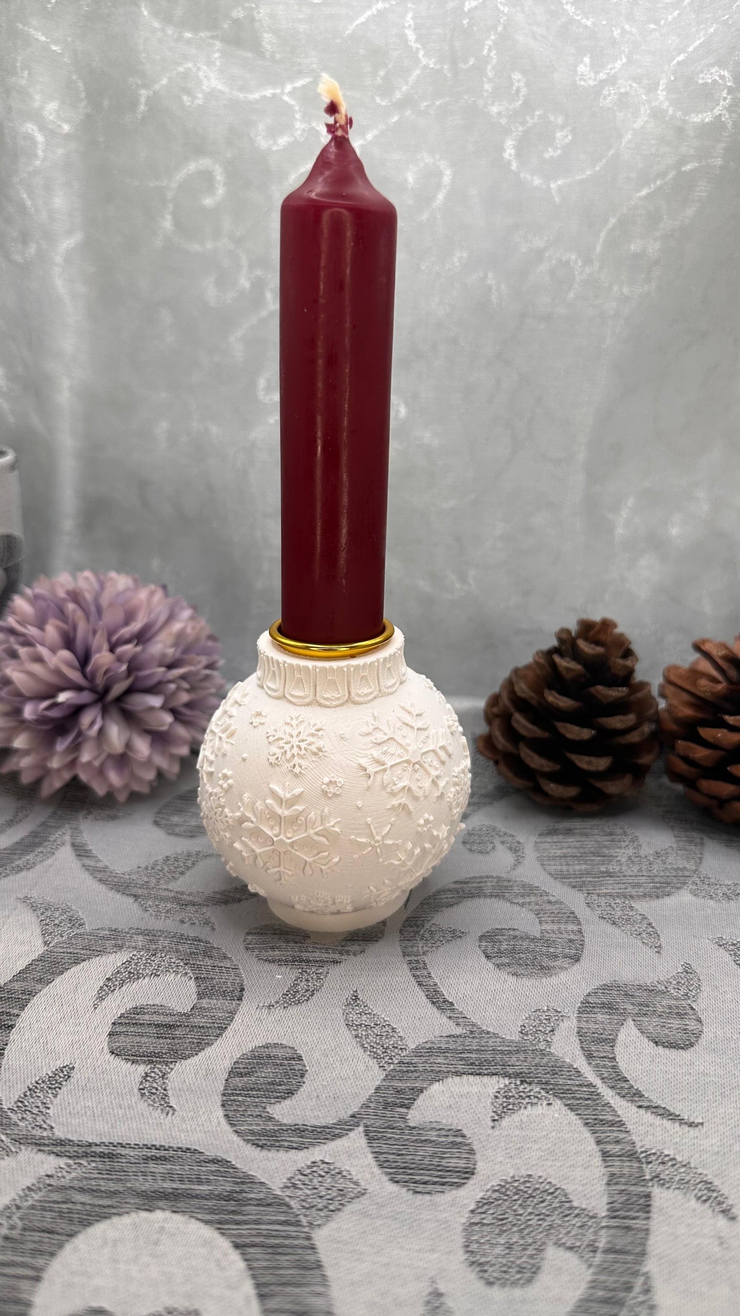 Weiße Keracraft-Weihnachtskugel als Stabkerzenhalter mit Schneeflockenrelief und roter Kerze.
Herzberg Crafts