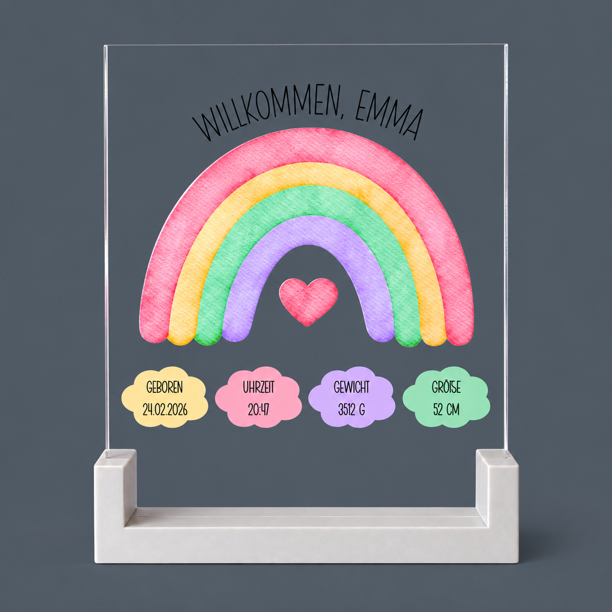 Personalisiertes Geburtsschild aus transparentem Acryl mit Regenbogen, Geburtsdaten und hellgrauem Sockel auf blaugrauem Hintergrund
