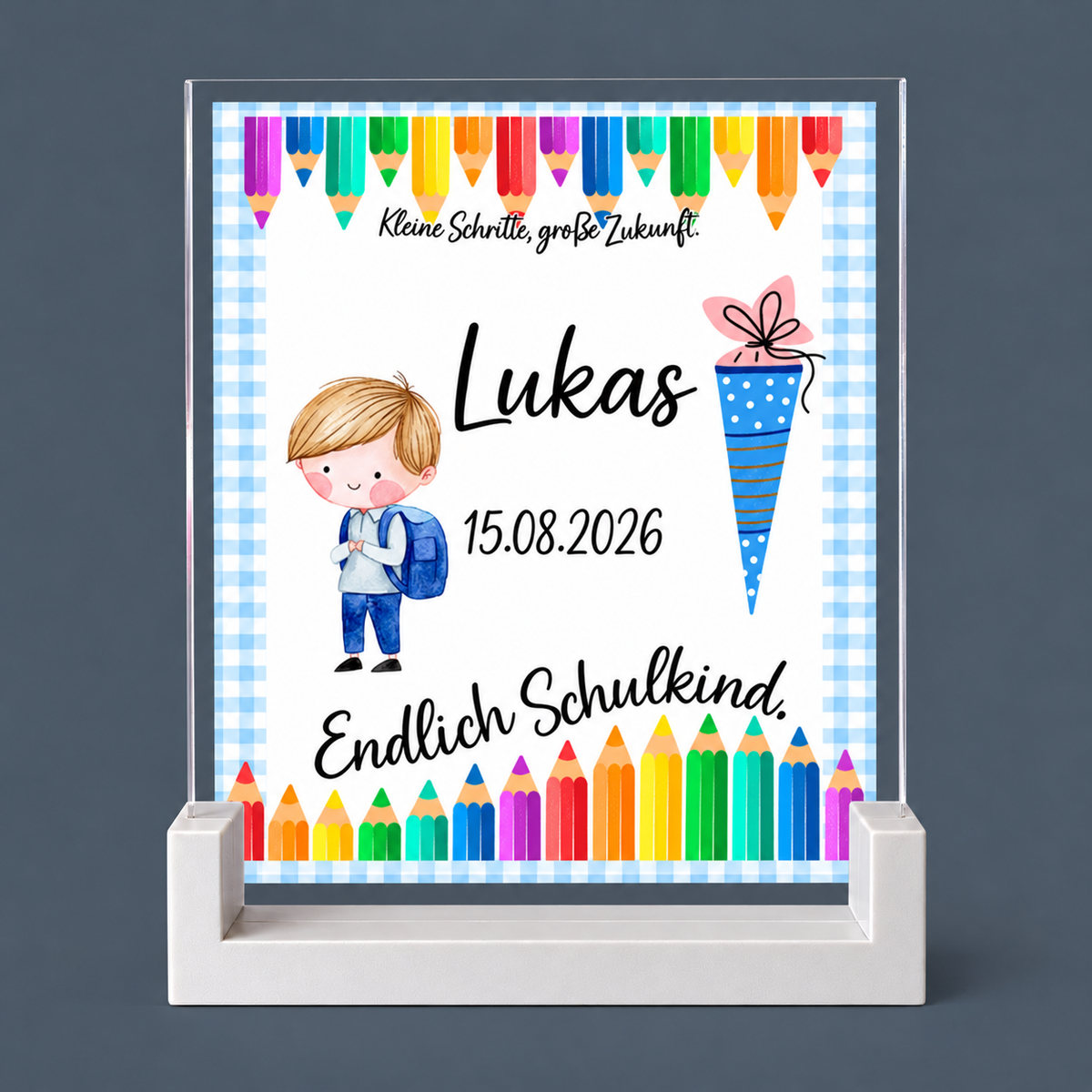 Personalisiertes Schuleingangsschild für Lukas mit bunten Stiften, Schulkind, Schultüte und blau-weiß kariertem Rahmen auf weiß bedruckter Fläche mit transparentem Acrylrand im PLA-Sockel