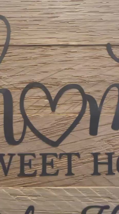 Video von Handgefertigtes Deko-Türschild mit weißem Keracraftring, Vinylschriftzug auf Holzklötzchen ‚home sweet home bei den Herzis‘ und Burgundy Makramee-Anhänger, an weißer Wand.
Herzberg Crafts