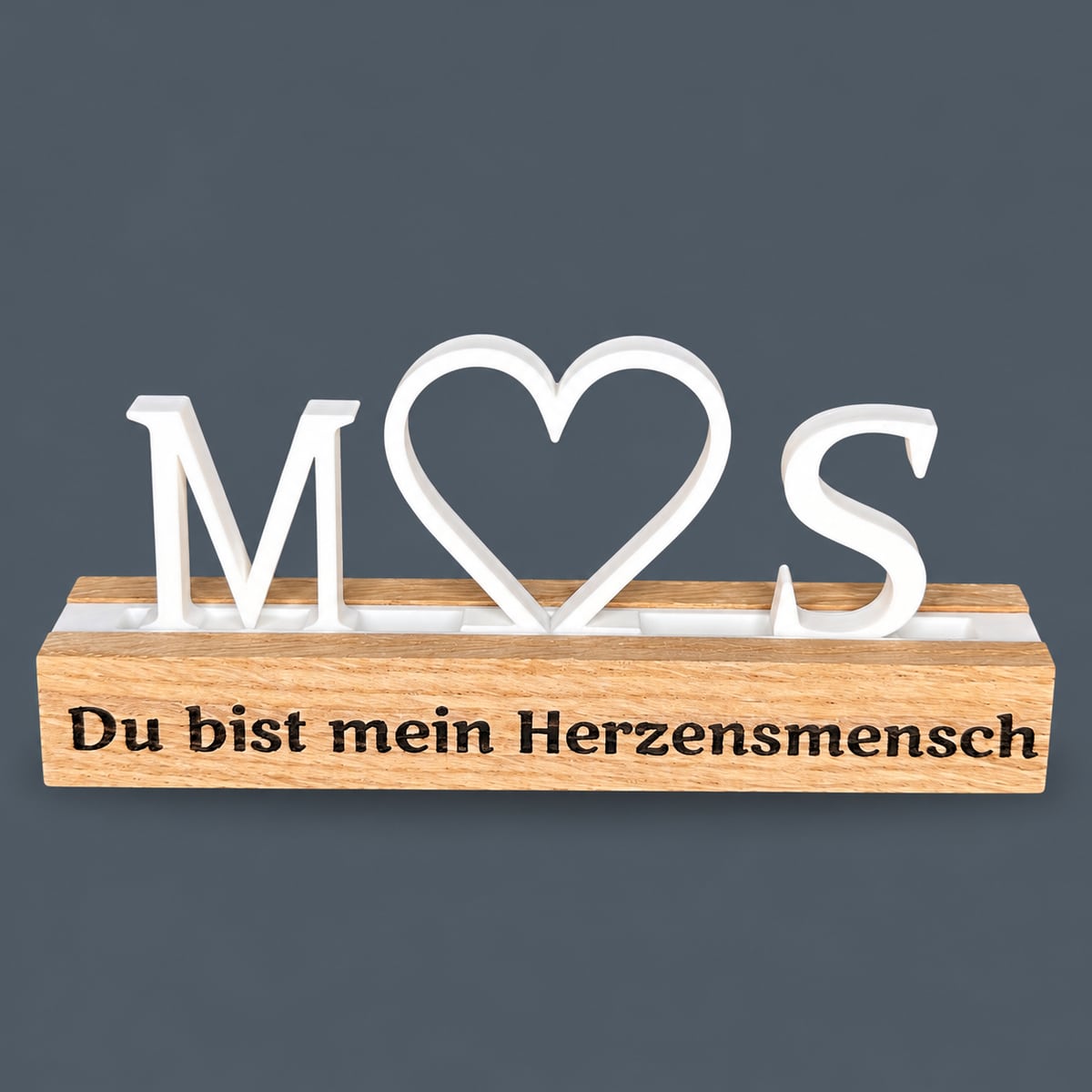 Personalisierter Deko-Aufsteller mit weißen Initialen M und S, Herz und Eichenholzsockel mit Gravur Du bist mein Herzensmensch auf blaugrauem Hintergrund